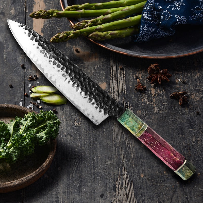 Decorative chef's knife with a colorful handle on a wooden surface with vegetables.